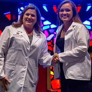 HSU Physician Assistant student and professor dressed in white lab coats shaking hands